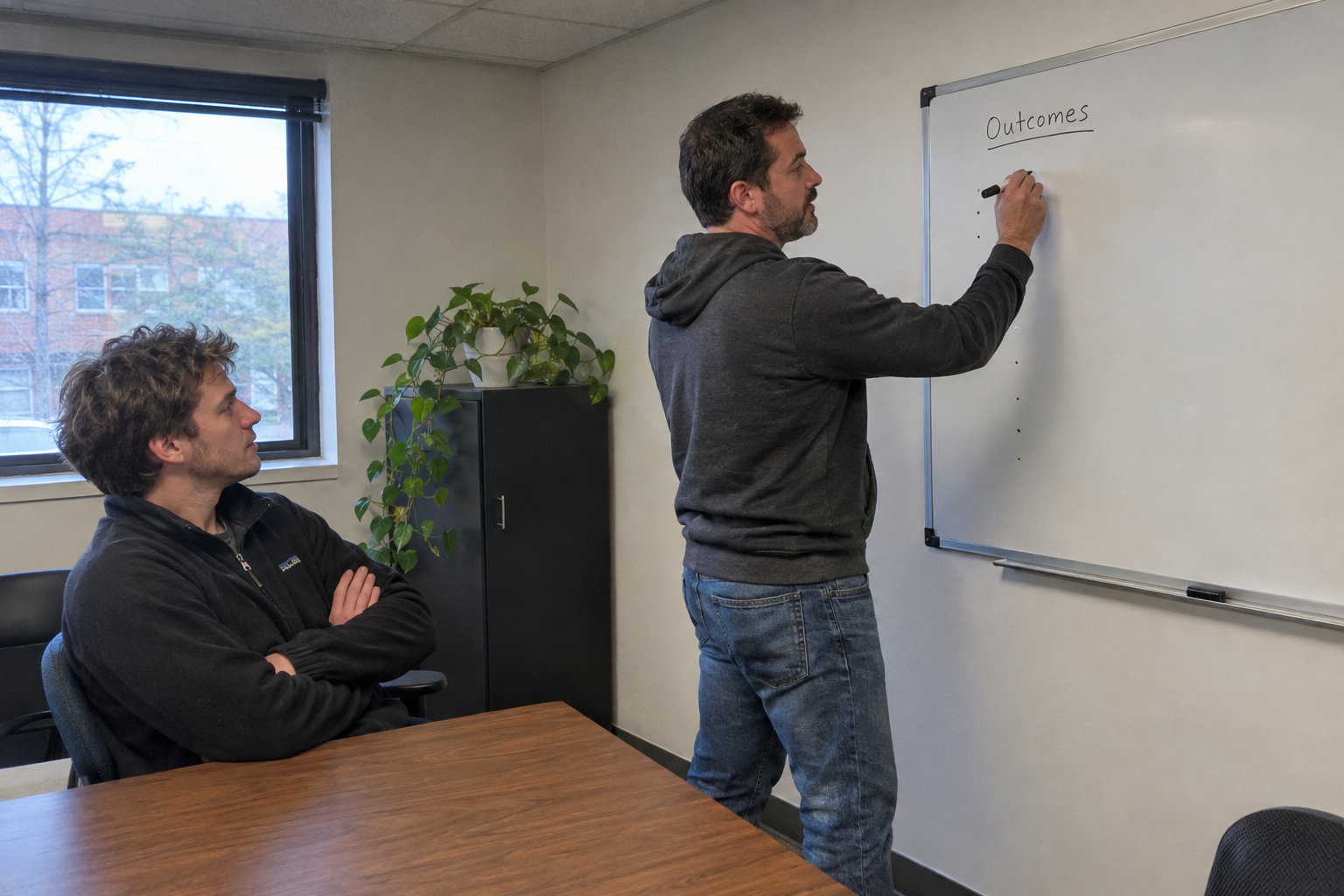 An owner and a young technician go over two printed scorecards together at a shared desk.