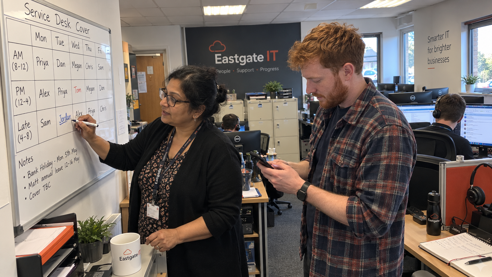 Service lead and technician revise shift coverage on a whiteboard while addressing help desk burnout concerns.