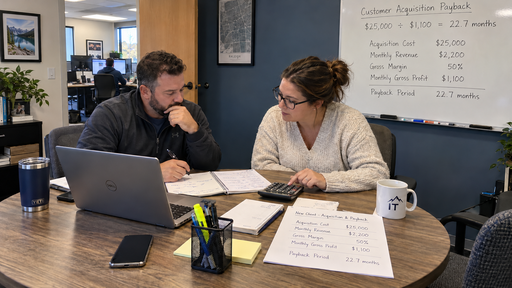 Two owners at a table with an MSP customer acquisition cost worksheet, calculator, and laptop.