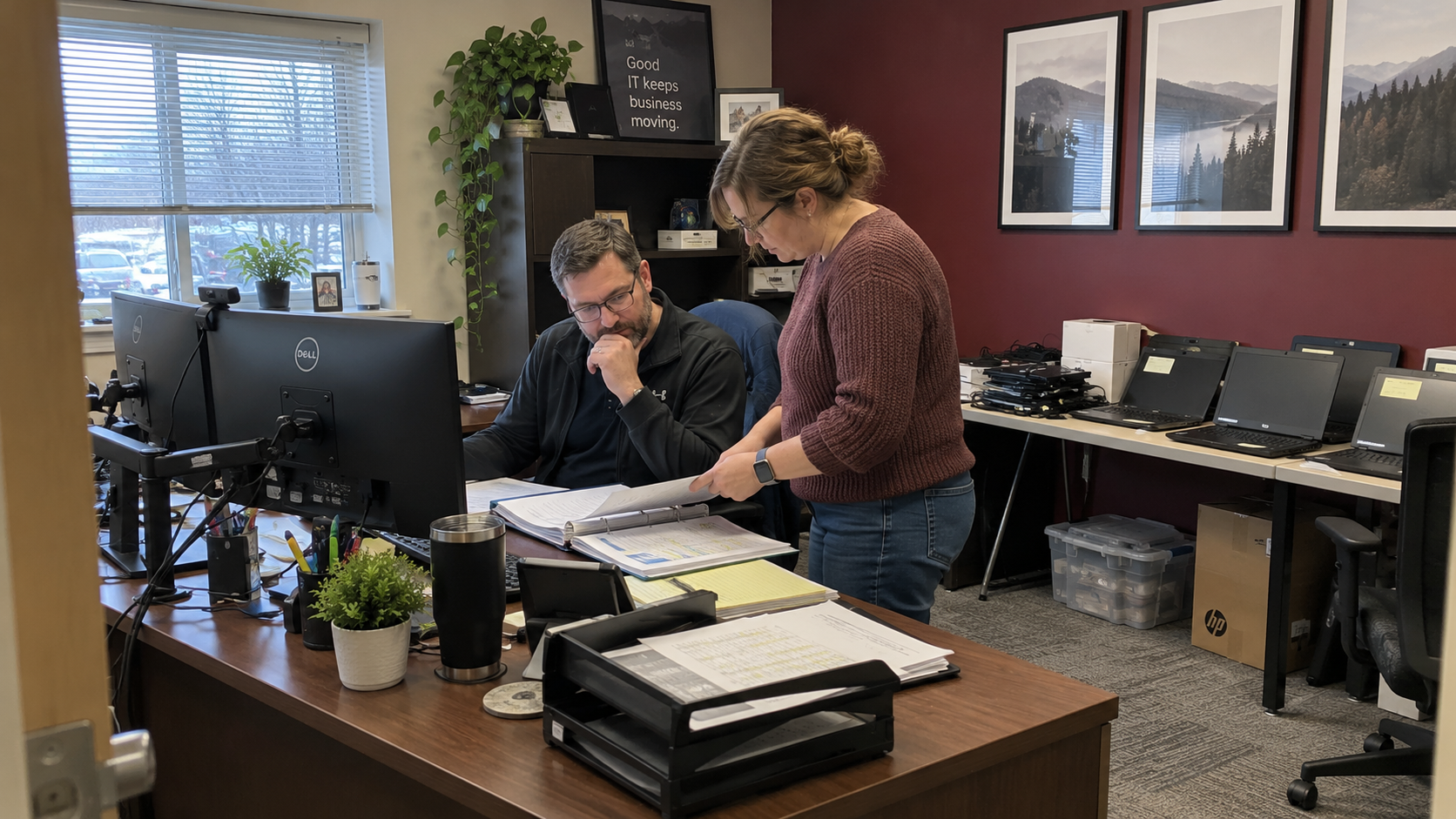 An MSP owner and bookkeeper review client payment records beside office workstations and staged laptops