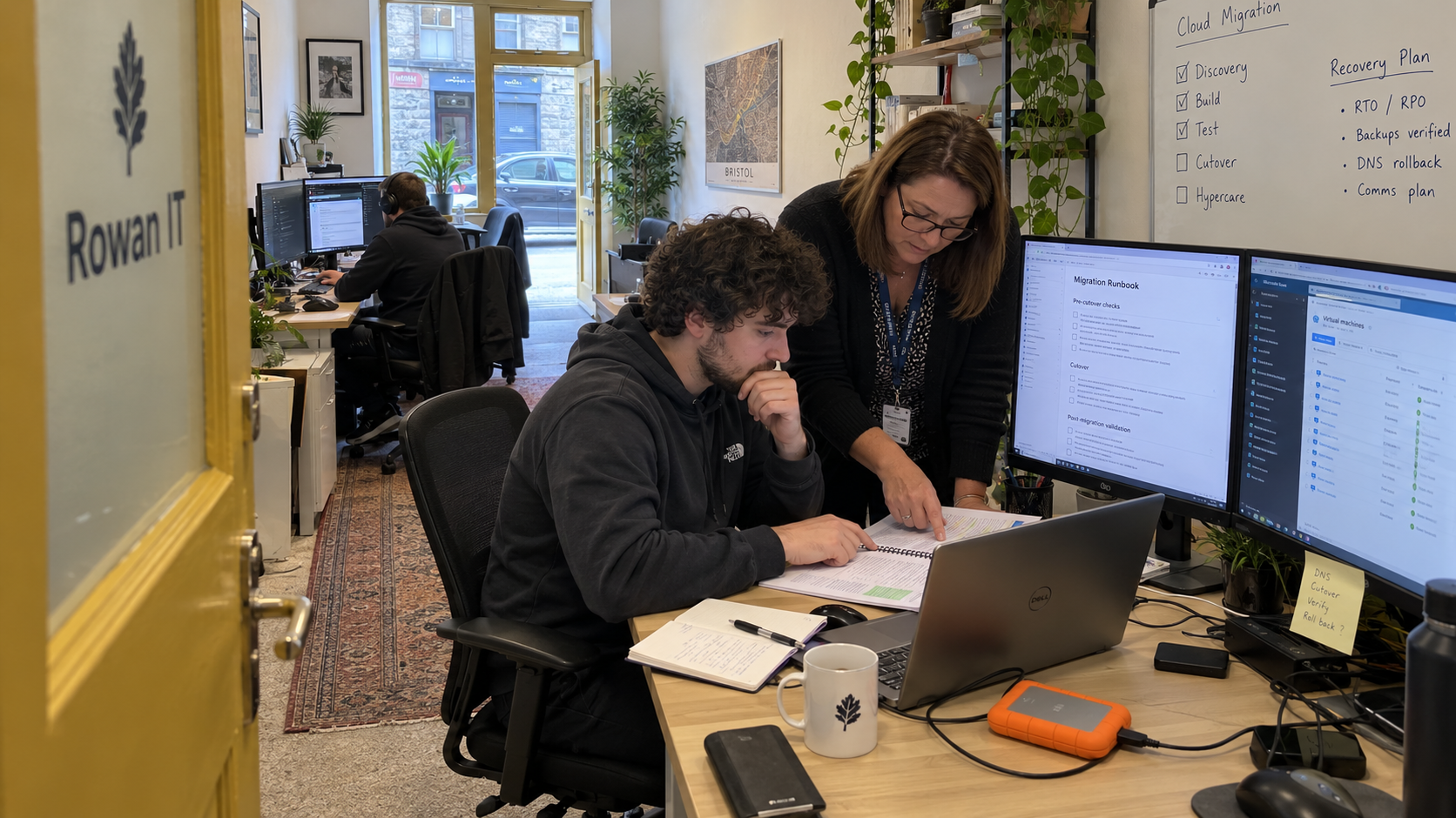 MSP engineer and coordinator review a cloud migration plan beside their project workstation