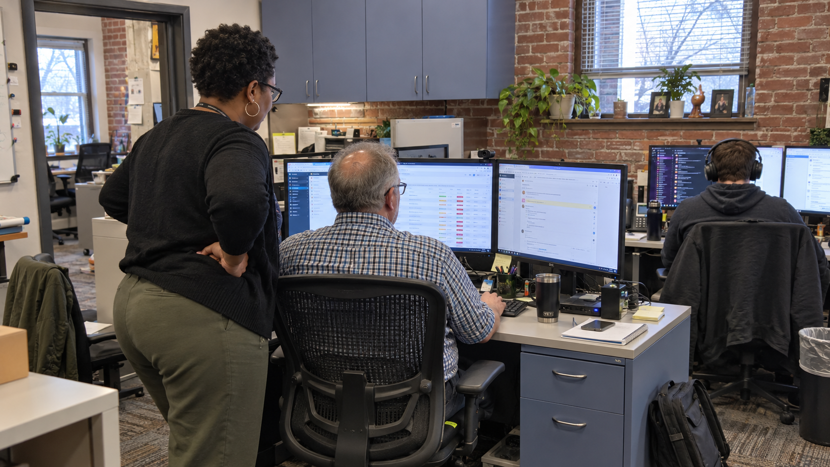 Team lead and technician review support workstations for ticket queue management at a small MSP