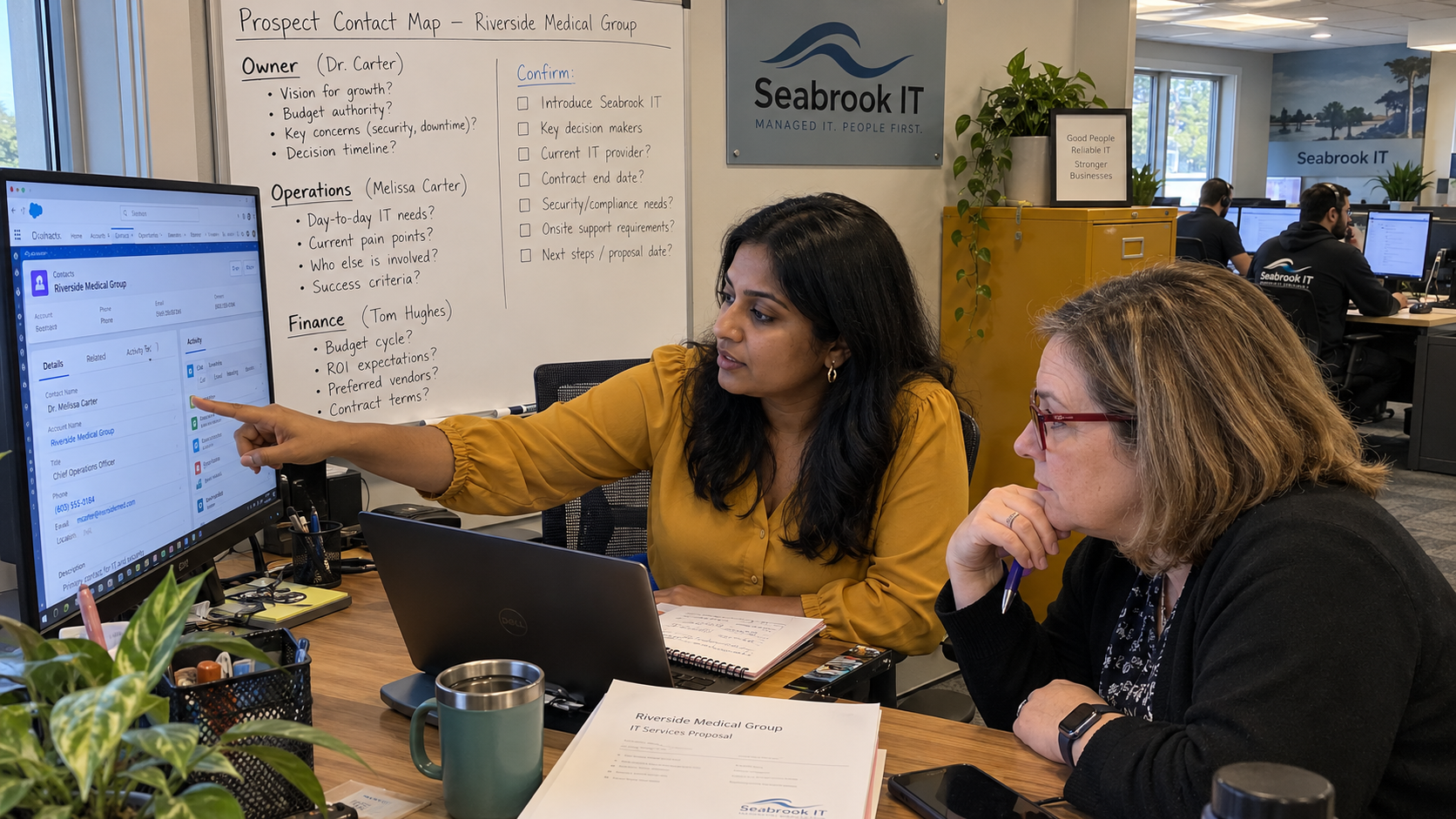 MSP sales colleagues review a buying committee contact map and CRM record before preparing a proposal.