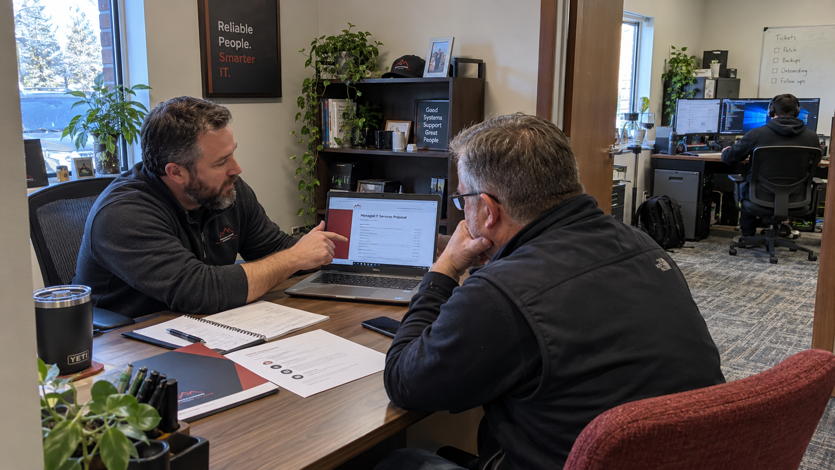 MSP owner and client review a proposal to move from break fix to managed services at a meeting desk