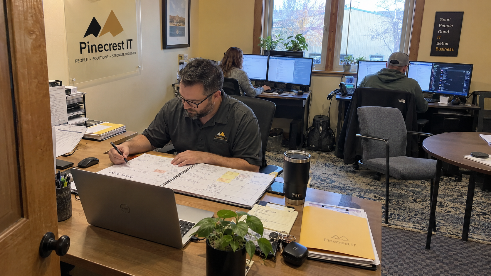 Account manager plans how many clients per vCIO to assign using his desk calendar in an MSP office.