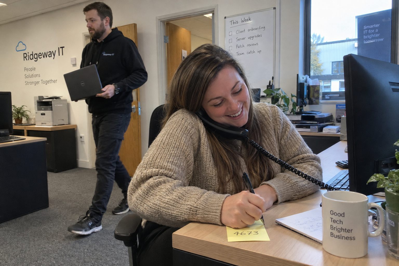 A woman notes a phone introduction for an MSP referral program while a colleague carries a client laptop