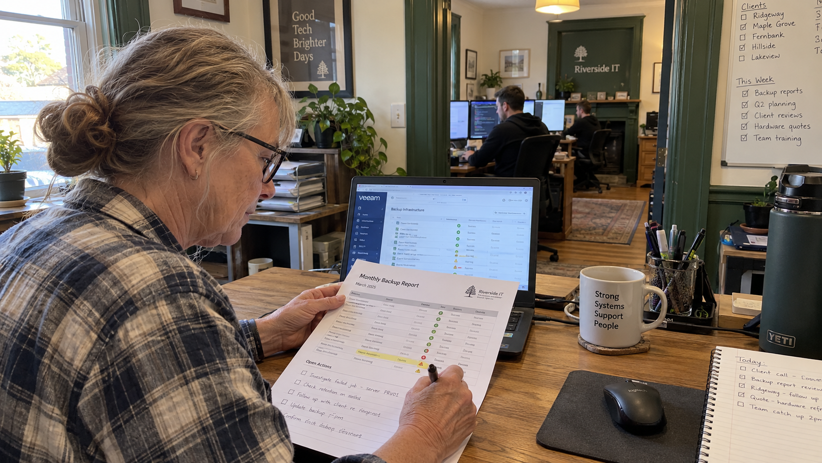 MSP account manager checks a printed backup report against a laptop and marks an open action
